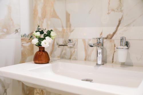 a bathroom sink with a vase of flowers on it at AMANTE Hotel - Bern Airport in Belp