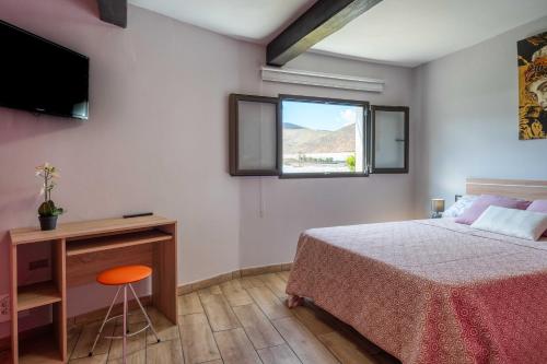 ラスパルマス・デ・グランカナリアにあるLas Fajanas de Gáldarのベッドルーム1室(ベッド1台、デスク、窓付)