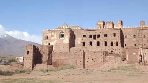 an old brick building with a mountain in the background at Dar adiafa dar asalam in Aït Benhaddou