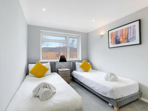 1 dormitorio con 2 camas y ventana en 5 MINS to Slough Trading Estate - Free Onsite Parking, WiFi - Sleeps 4 en Slough