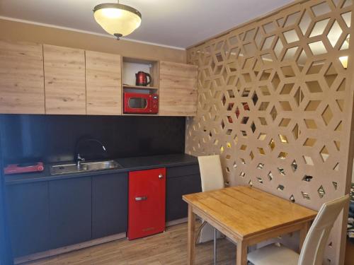 eine Küche mit einem roten Schrank und einem Tisch in der Unterkunft WILLA VASCO NAWIGATOR in Rewa