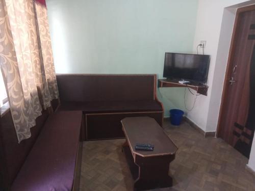 uma pequena sala de estar com um sofá e uma televisão em Royal Queen Residency em Ooty
