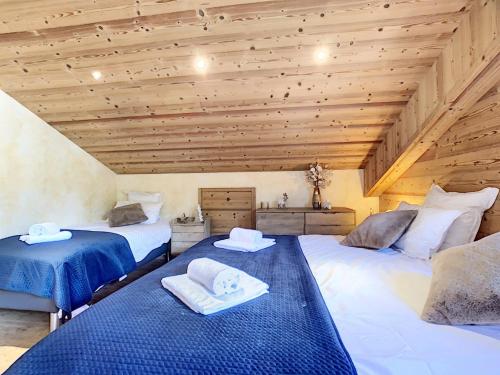 two beds in a room with wooden ceilings at Chez Arsene - appartement - 10 pers - proche piste in Les Gets
