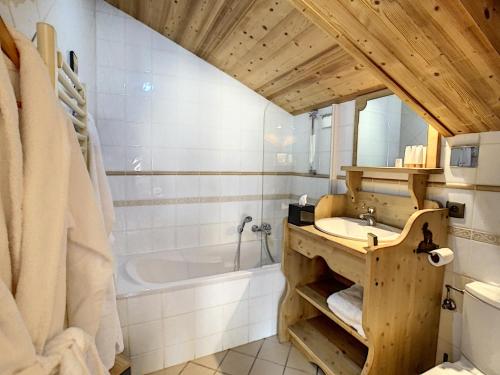 een badkamer met een wastafel en een bad bij Chez Arsene - appartement - 10 pers - proche piste in Les Gets