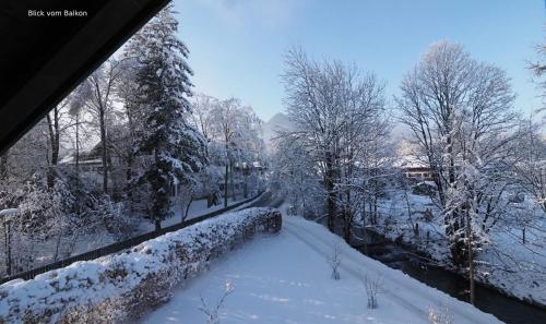 una calle cubierta de nieve con árboles y una carretera en Bamberger Monika, en Fischbachau