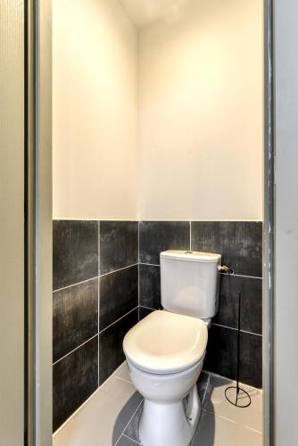 a toilet in a bathroom with black tiles at le maquens - parking gratuit - wifi - netflix in Carcassonne