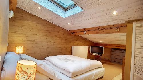 une chambre avec un lit et une lucarne dans l'établissement Clos 28 - appartement - 6pers - proche centre, aux Gets