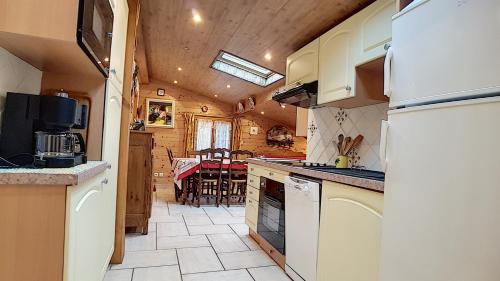 une cuisine avec des appareils électroménagers blancs et une salle à manger dans l'établissement Clos 28 - appartement - 6pers - proche centre, aux Gets