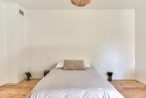 a bed in a room with white walls at le maquens - parking gratuit - wifi - netflix in Carcassonne
