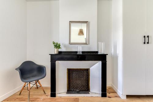 a black fireplace with a black chair and a mirror at le maquens - parking gratuit - wifi - netflix in Carcassonne