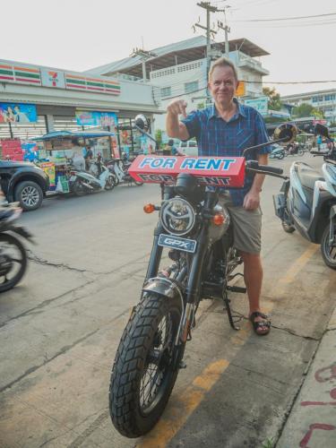 a man is sitting on a motor cycle at Noot's Guesthouse in Kanchanaburi