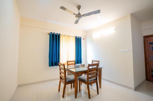 a dining room with a table and chairs and a ceiling fan at Elegance Serviced Apartment in Mysore