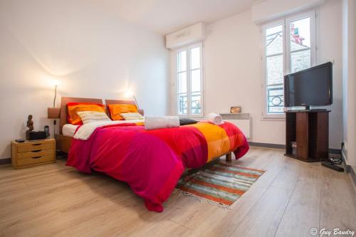 um quarto com uma cama grande e uma televisão de ecrã plano em Chic apart with parking near Paris em Colombes