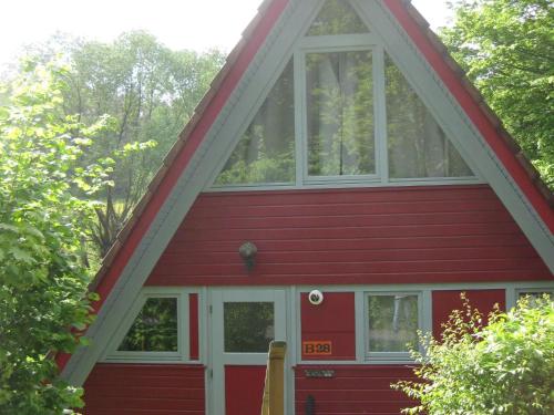 a red house with a large window at Wooden bungalow with a terrace in a wooded area in Berneburg