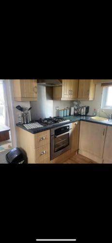 a kitchen with wooden cabinets and a stove top oven at Cosy static caravan, hunstanton in New Hunstanton