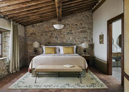 a bedroom with a bed and a stone wall at Castello di Casole, A Belmond Hotel, Tuscany in Casole dʼElsa