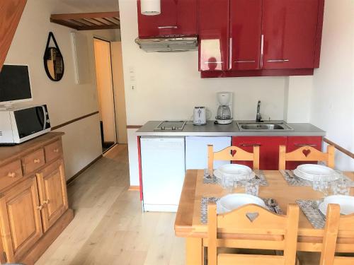 une cuisine avec une table et des chaises et un micro-ondes dans l'établissement Le Lion dor 2- appartement- 4pers - centre statio, aux Gets
