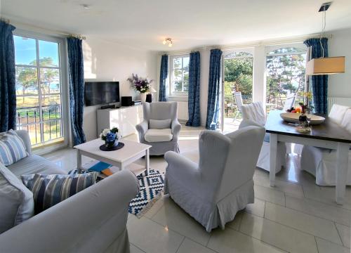 a living room with white furniture and a table and chairs at Haus Meeresblick - Ferienwohnung Strandloeper C 2.02 (Ref. 134796) in Baabe