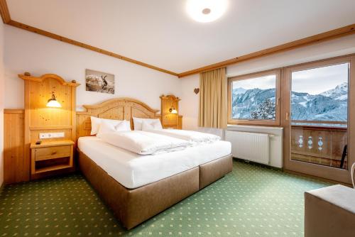 a bedroom with a large bed and a large window at Astegg, Alpengasthof in Finkenberg