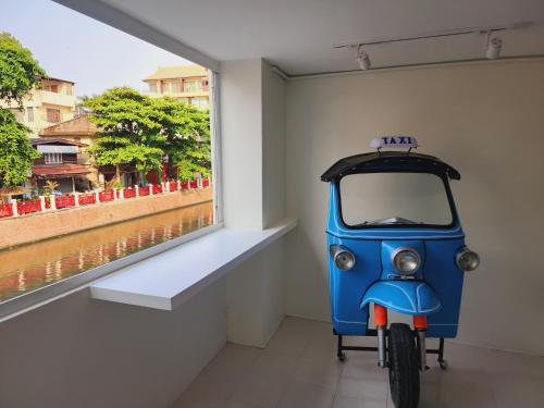 Una pequeña motocicleta azul estacionada junto a una ventana en Line Bangkok Hostel en Bangkok