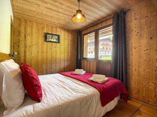 - une chambre avec un lit doté de draps rouges et une fenêtre dans l'établissement Rossin - appartement - 8 pers - ski-in-out, aux Gets