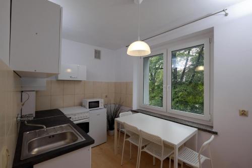 a kitchen with a sink and a table with chairs at Apartament Słoneczny 3 in Opole