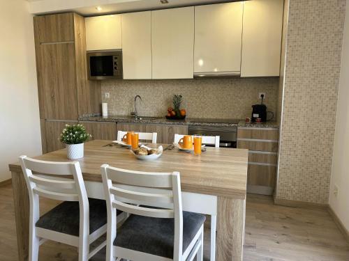 Una cocina con una mesa de madera y sillas blancas. en ELITE RESIDENCE 10F, en Portimão