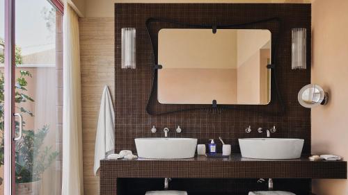 a bathroom with two sinks and a mirror at Castello di Casole, A Belmond Hotel, Tuscany in Casole dʼElsa