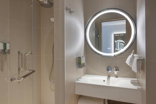 a bathroom with a shower and a sink and a mirror at Hampton By Hilton Kuwait Salmiya in Kuwait