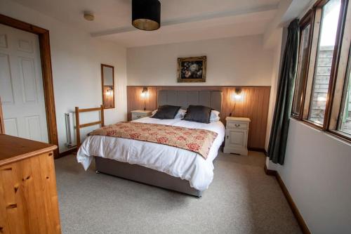 a bedroom with a large bed and two windows at The Linhay at Hewish Mill in Barnstaple