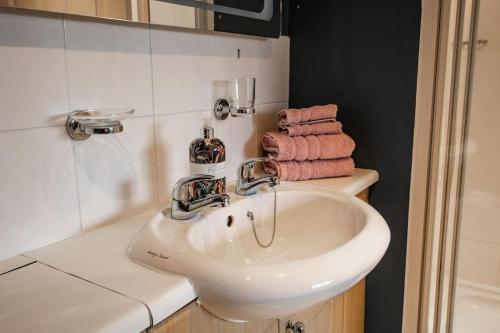 巴恩斯特珀爾的住宿－The Linhay at Hewish Mill，浴室设有白色水槽和粉红色毛巾