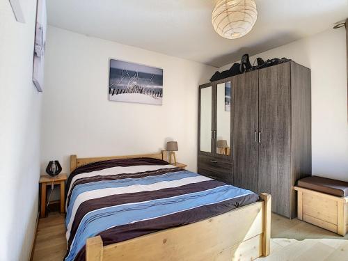 une chambre avec un lit et une armoire en bois dans l'établissement Le Schuss - appartement - 4 pers - centre ville, aux Gets