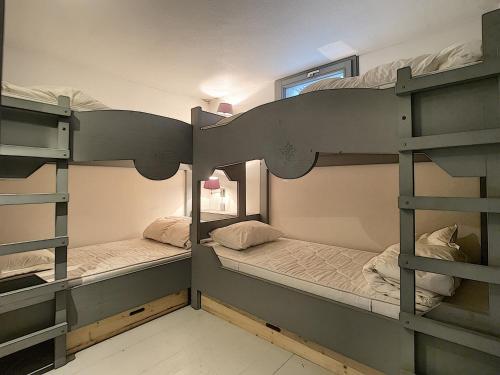 two bunk beds in a small room with a window at Mont Caly - appartement - 8 pers - centre in Les Gets