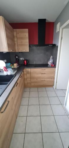 une cuisine avec des armoires en bois et un sol carrelé dans l'établissement 2 Chambres-Phonique-Parking sécurisé-Climatisation-DALLE BETON- Géré par Presta-Zen'Services, à Verdun-sur-Meuse