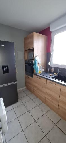 une cuisine avec des armoires en bois et un évier dans l'établissement 2 Chambres-Phonique-Parking sécurisé-Climatisation-DALLE BETON- Géré par Presta-Zen'Services, à Verdun-sur-Meuse