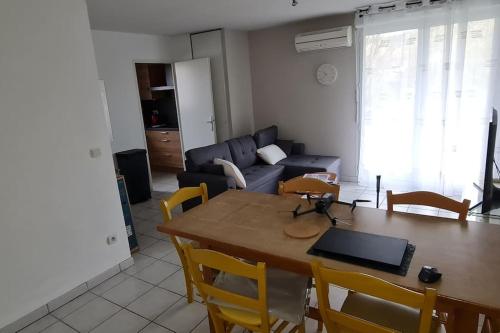 un salon avec une table et un canapé dans l'établissement 2 Chambres-Phonique-Parking sécurisé-Climatisation-DALLE BETON- Géré par Presta-Zen'Services, à Verdun-sur-Meuse