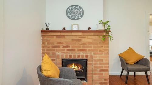 a living room with a brick fireplace with two chairs at Family Retreat Woy Woy in Woy Woy