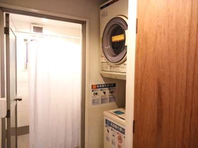 a bathroom with a door leading to a laundry room at Guesthouse Banvina in Kagoshima