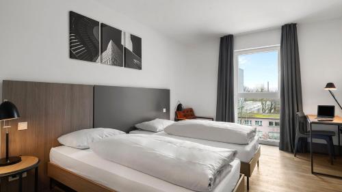 a hotel room with two beds and a desk at SMARTments connect Frankfurt City Ost in Frankfurt/Main