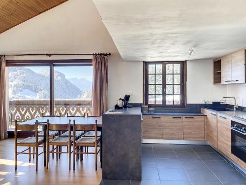 une cuisine avec une table et des chaises ainsi qu'une grande fenêtre dans l'établissement Cornuts 3 - appartement - 7pers, aux Gets