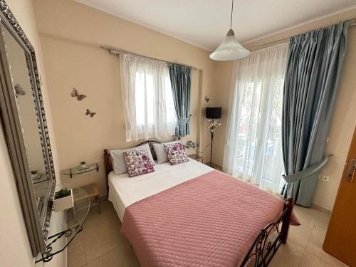 a bedroom with a bed with pink sheets and windows at Orfeas Sea View House in Archangelos