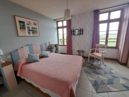 ein Schlafzimmer mit einem großen Bett mit einer rosa Decke in der Unterkunft LOCATION à COUCY LE CHATEAU in Coucy-le-Château-Auffrique