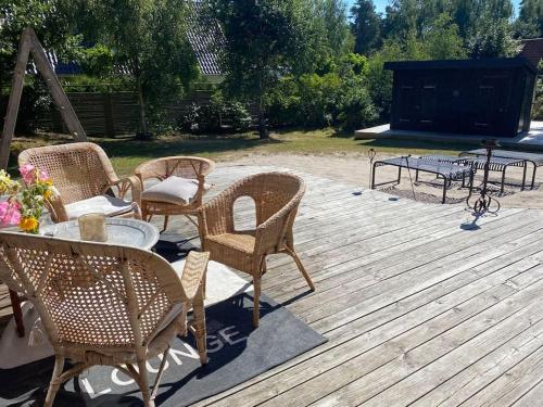 a group of chairs and tables on a wooden deck at Sandpärlan 8 - Havet Österlen in Simrishamn