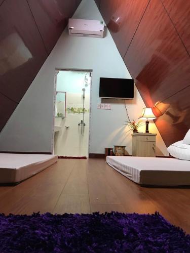 a attic room with two beds and a tv at Thung Lũng Ba Đồi Chè in Mộc Châu