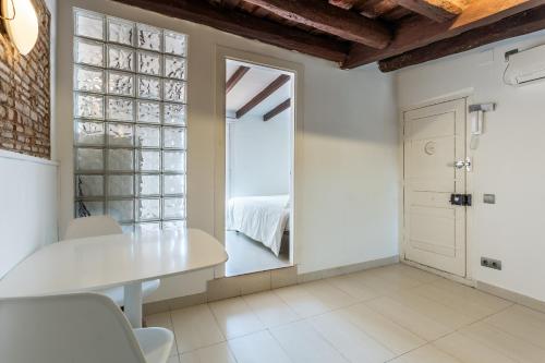 a white dining room with a table and a window at Apartamento La boqueria Atic in Barcelona
