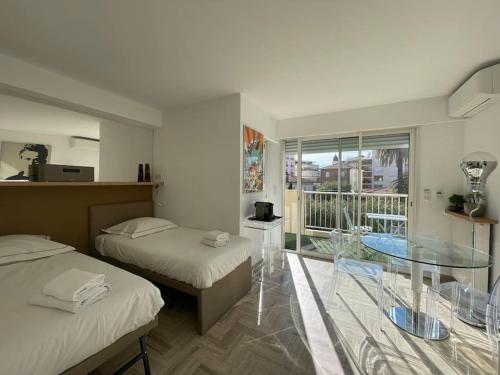 Cette chambre comprend 2 lits et une table en verre. dans l'établissement L'Olivier - Croisette Martinez, Studio sur cour, plage 1 min, à Cannes