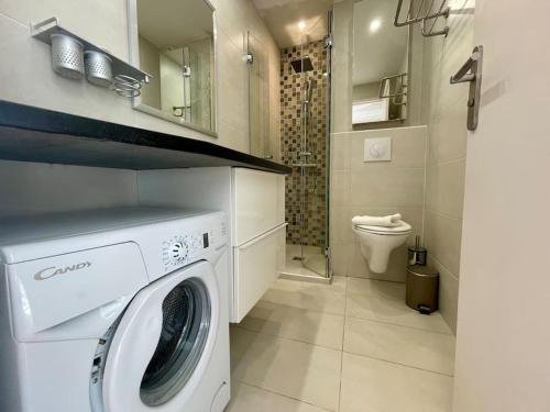 une machine à laver dans une salle de bain avec toilettes dans l'établissement L'Olivier - Croisette Martinez, Studio sur cour, plage 1 min, à Cannes