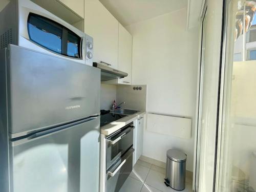 une cuisine avec un réfrigérateur en acier inoxydable et un évier dans l'établissement L'Olivier - Croisette Martinez, Studio sur cour, plage 1 min, à Cannes