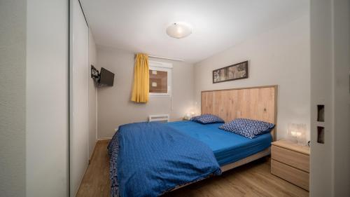 une chambre avec un lit bleu et une fenêtre dans l'établissement C du Verdon -2202- Magnifique Appt 5 pers, à La Foux