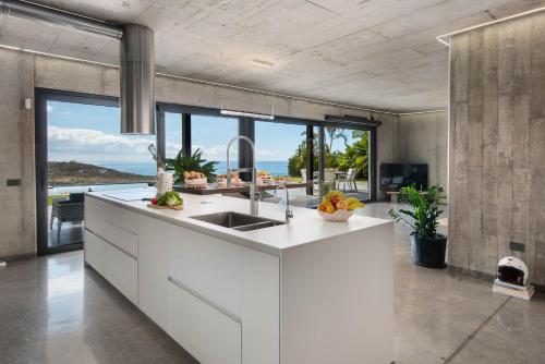 una cucina con armadi bianchi e vista sull'oceano di Karat Atelier de la vega a Playa Paraiso